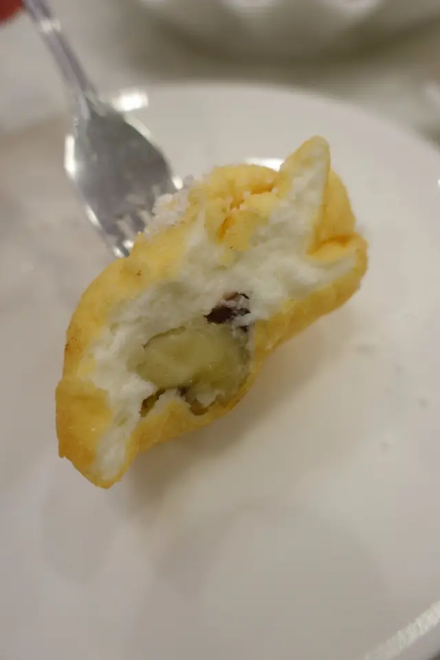 表面灑上糖粉，包住紅豆餡及香蕉，意想不到兩者可以夾得來！