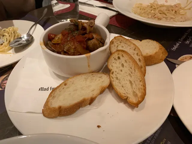 Sauteed baby octopus with clams in spicy garlic tomato sauce, served with sliced baguette